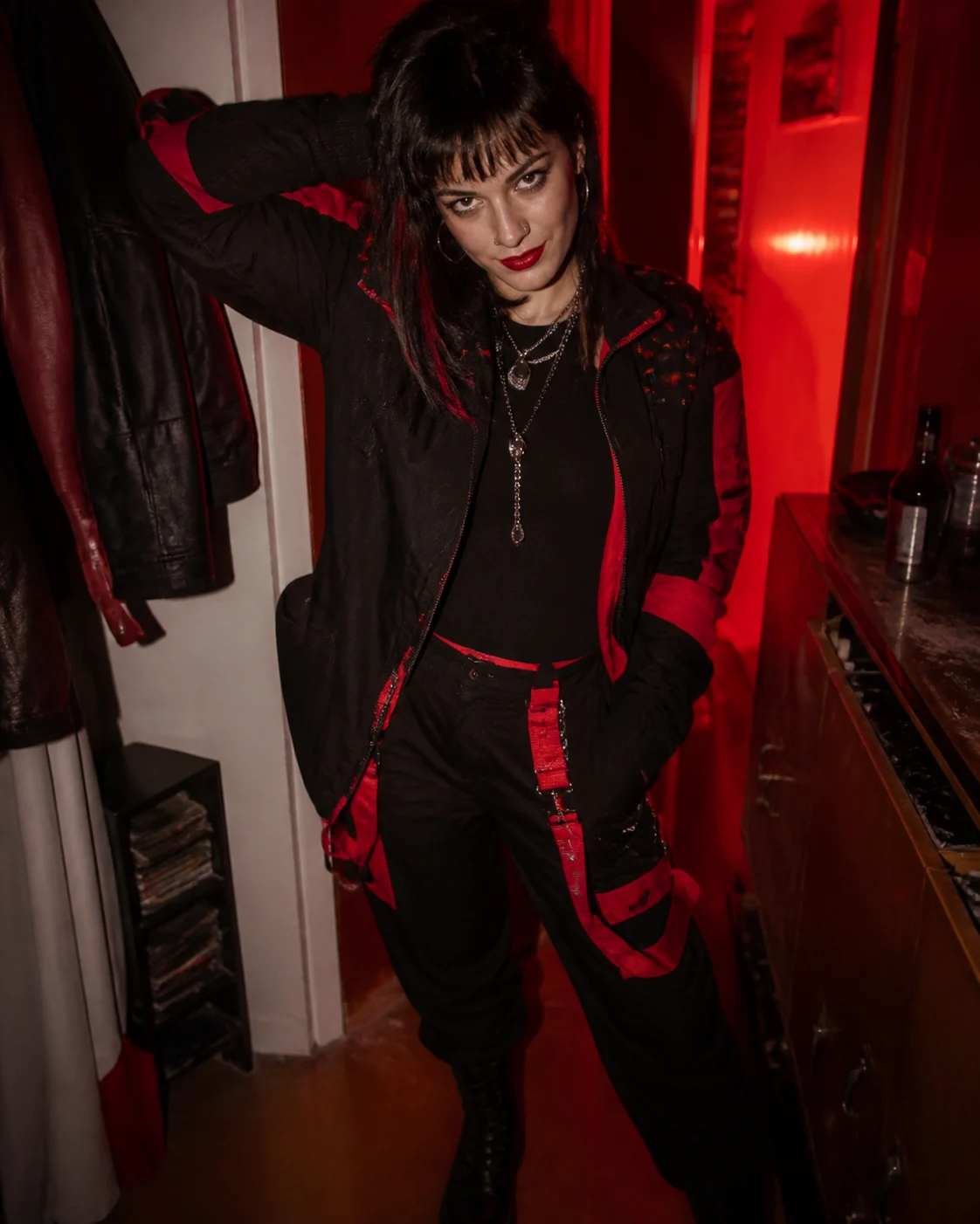 An adult woman in bold black-and-red streetwear under hard flash.