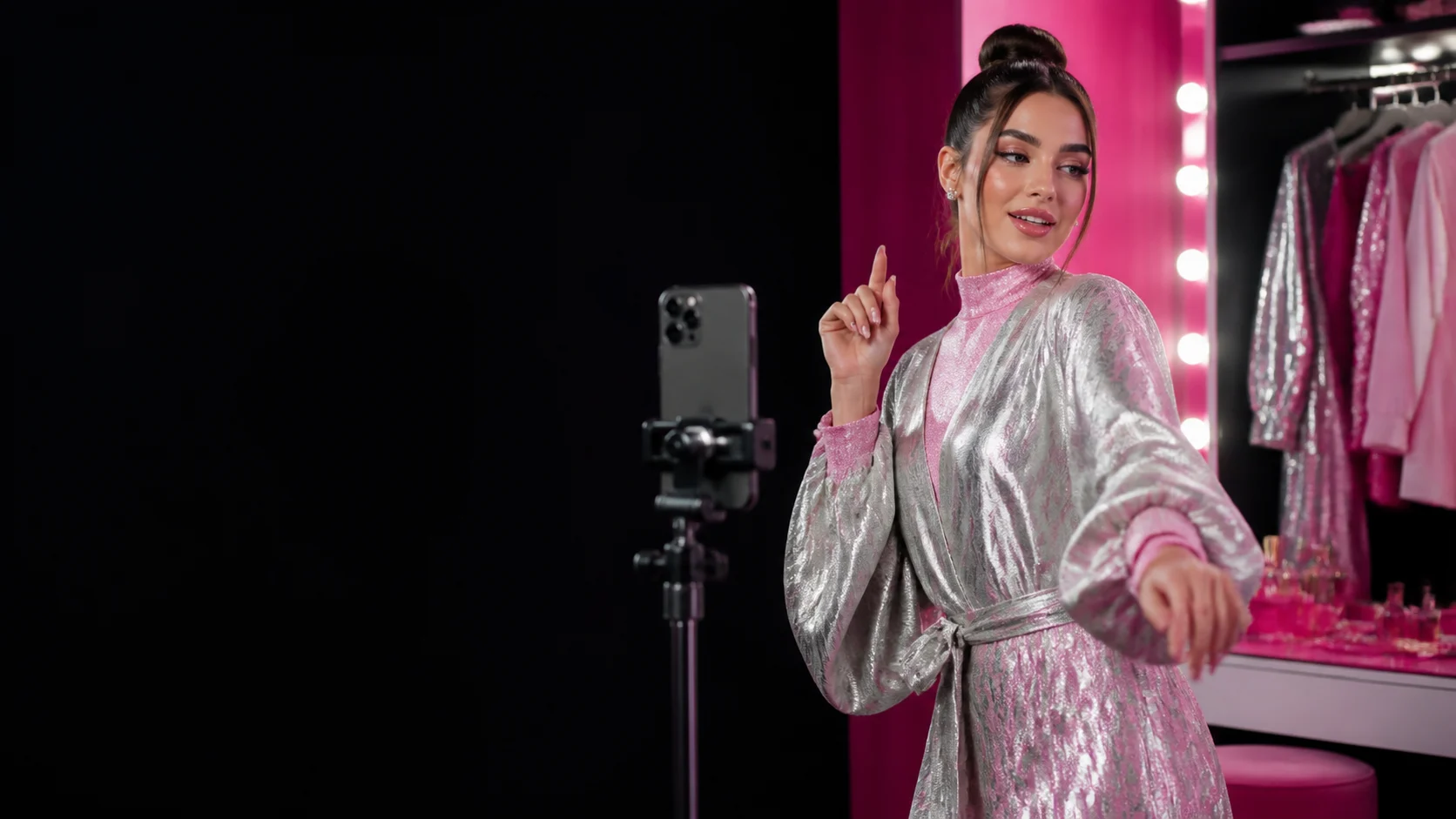 An adult creator films a glossy vertical social reel in a black-and-pink dressing room.