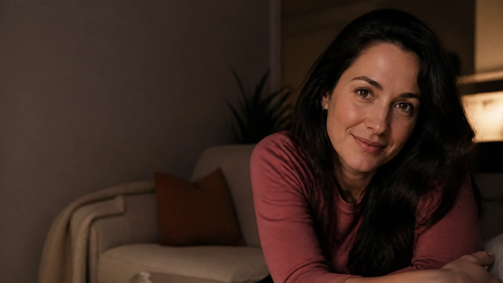 An adult brunette shares a warm private moment in a low-lit everyday apartment.